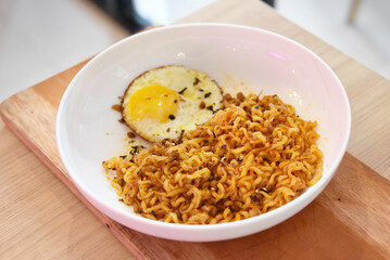 Spicy korean noodles in a bowl with egg served on the table. 