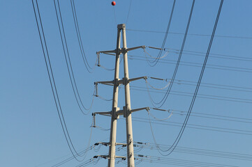 Transmission tower supporting overhead power lines with  orange visibility round marker