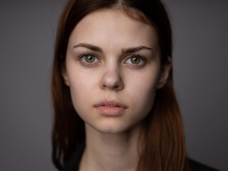 Naklejka premium Portrait of a red-haired woman on a gray background beautiful face model cropped view