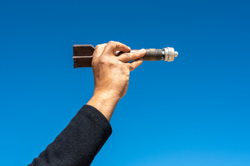 Mortar shell in man hand ower sky background.