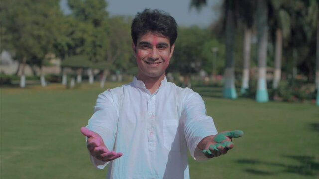 Indian male throwing bright Gulal in the air celebrating the festival of colors. Medium shot of a cheerful man in traditional wear enjoying playing with Abeer during Holi party