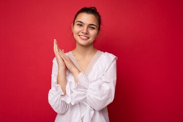 Young beautiful european stylish brunette woman wearing white blouse isolated over red background with positive sincere emotions. Simple and natural looking at the camera. Free space