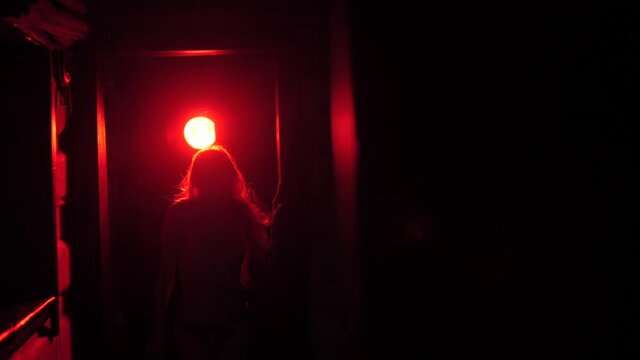 A girl with long hair waving her head. A beautiful girl in front of the red light.