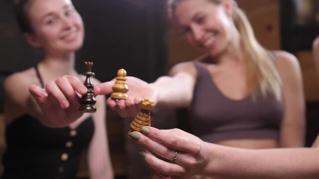 Three chess pieces in the hands of happy girls. A game of chess. Girls play an intellectual game