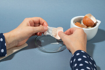Women hands remowing eggshell membrane. Zero waste cosmetics.