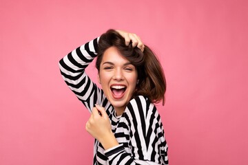 Fototapeta premium Photo shot of cute attractive pretty joyful funny young brunette woman wearing casual striped longsleeve isolated over colorful background with copy space