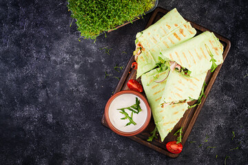 Fresh tortilla wraps with chicken and fresh vegetables on wooden board. Chicken burrito. Healthy food concept. Mexican cuisine. Top view, overhead © timolina