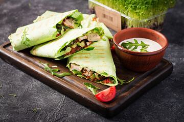 Fresh tortilla wraps with chicken and fresh vegetables on wooden board. Chicken burrito. Healthy...