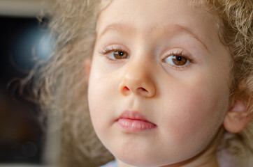 Chubby little girl with light brown eyes and blond hair is looking at the camera. Selective Focus Eyes