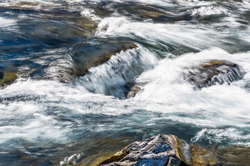 Creek or stream water flowing past rocks and stones