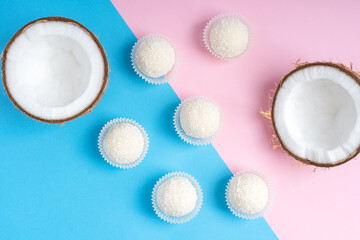 Top view of coconut truffles or energy balls with a filling of sweetened shredded coconut, condensed milk and curd cheese laying on trendy colorful pink and blue background. Horizontal image
