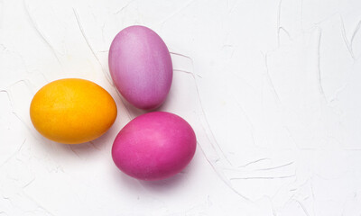 Easter bright eggs lay flat on a white textured background with a copy of the space