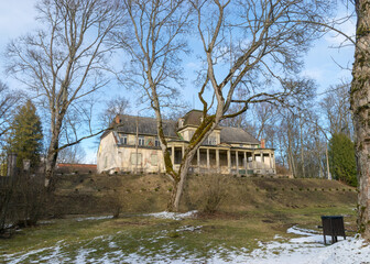 landscape with Burtnieki manor building, early spring in the manor park, bare tree silhouettes, Burtnieki manor