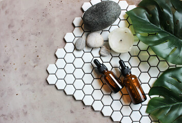 A glass bottle with aromatic oil or serum on a stone and little twig with flowers near. Natural Organic Spa Cosmetic concept. Flatlay concept.