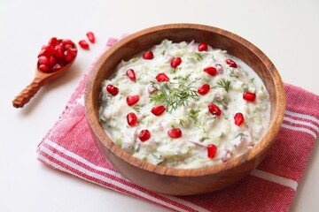 Indian Fresh sauce or condiment called Raita. Yogurt mixed with grated cucumber, onions, pomegranate and spices. Garnished with fresh coriander. Copy space.