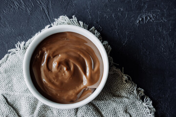 homemade chocolate pudding in white porcelain plate on dark background. homemade recipes for...