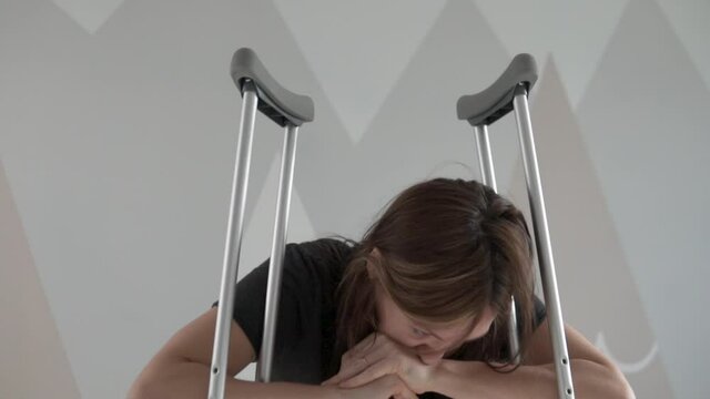 Close-up, the woman is sad leaning on crutches.
