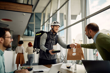 Fototapeta premium Happy courier delivering food order to business people who are working at office building.