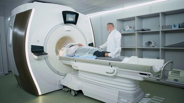 Magnetic resonance imaging in the modern hospital, adult man doctor performs a magnetic tomographic examination of a young woman, MRI, modern technologies in medicine.