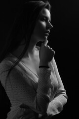 Obraz premium Black and white portrait of a young brunette woman in a studio on a black background