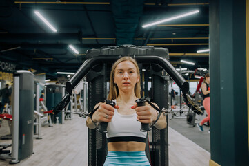 Obraz na płótnie Canvas Athletic women training chest on a simulator at gym