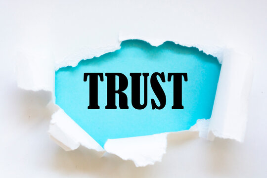 Torn white paper revealing the word Trust