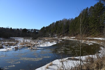 picturesque landscape of early spring on the river on a sunny day. Snow melting, nature awakening