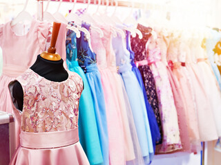Elegant dresses for little girls on hangers in store