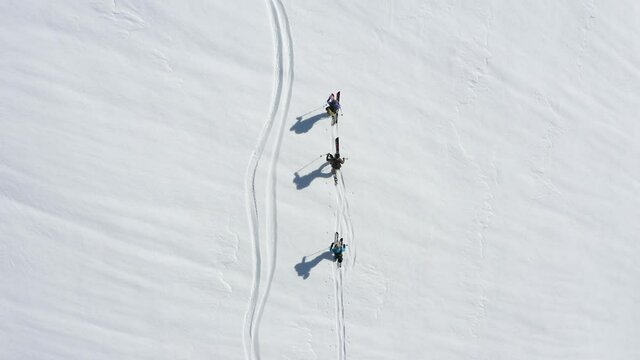 Splitboard or ski touring drone shot of three persons from above.
