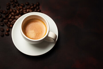White cup of coffee and coffee bean on dark background. Copy space. 