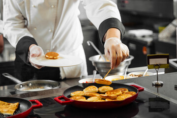 Restaurant chef cooking pancakes on a pan in the kitchen