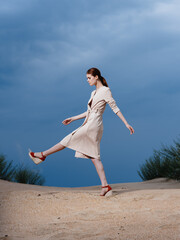 A woman walks along the beach in red sandals with a wide stride