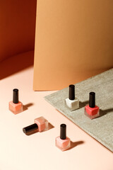 Set of nail polish bottles neutral natural colors on brick podium on beige background. Concept of pallete for french manicure, trendy modern stone platform for presentation of products