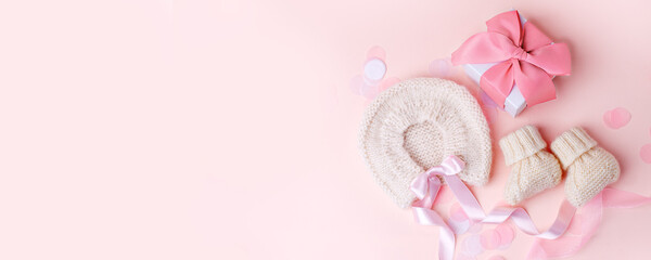 Beautiful composition with baby booties shoes, bonnet and gift box on pink background. Concept of baby shower party, pregnancy, mother day, first birthday holiday card, copy space, banner
