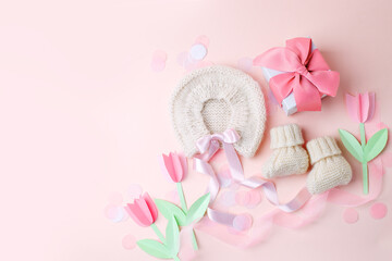 Beautiful composition with baby booties shoes, bonnet and gift box on pink background. Concept of baby shower party, pregnancy, mother day, first birthday holiday card, copy space, banner