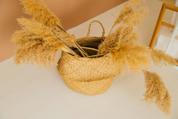 A wicker basket with panicles of reeds stands on the floor in the interior.