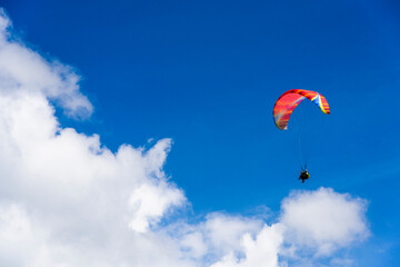 Fototapeta na wymiar Paragliding extreme Sport with blue Sky and clouds on background Healthy Lifestyle and Freedom concept