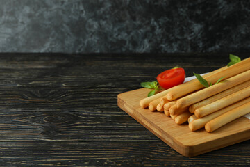 Board with grissini breadsticks on wooden table