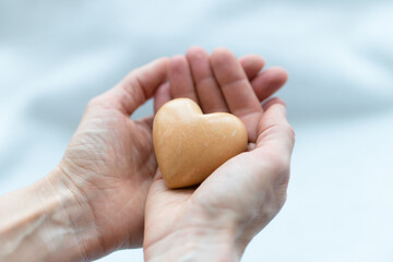 stone like heart holded in hands. concept of charity, love, donate and helping hand. International cardiology day