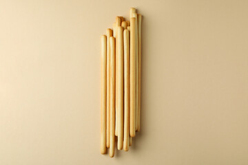 Tasty grissini breadsticks on beige background, space for text