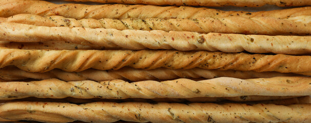 Tasty grissini breadsticks on whole background, close up