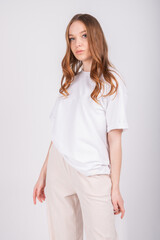 Sexy young girl wearing blank t-shirt. White wall background, fashion mockup