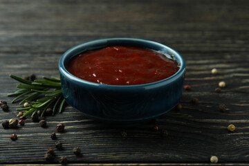 Bowl of barbecue sauce and spices on wooden background