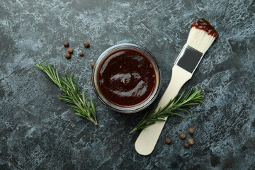 Barbecue sauce, spices and brush on black smoky background