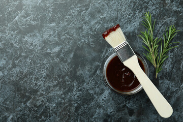 Barbecue sauce, rosemary and brush on black smoky background