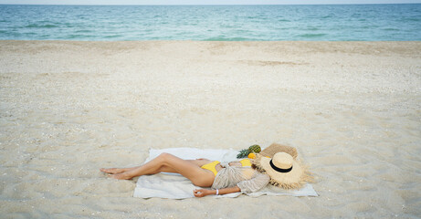 Fototapeta na wymiar relaxing woman lying and sunbathing at beach, beach accessories and fresh fruit on blanket