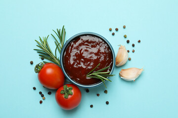 Bowl of barbecue sauce and spices on blue background