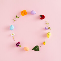 Naklejka na ściany i meble Creative Easter layout made of colorful eggs, spring flowers and leaves on pink background. Nature circle wreath flat lay.