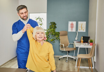 Physiotherapist treatment patient. Chiropractor holds patient's hand, shoulder joint treatment