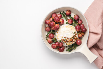 Baked camembert cheese with grapes, nuts, honey and thyme. White food background